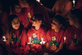 Kids at Camp UKANU holding candles by a campfire