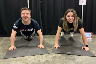 Two smiling people doing pushups together