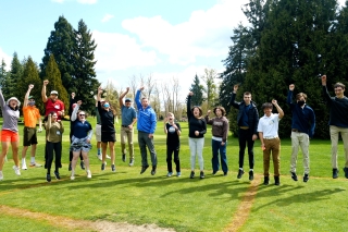 A group of people jumping and raising their arms on a golf course