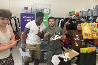 Four young people at a Project 48 gathering with one of them opening a box of new sneakers and one holding up a boxed pizza