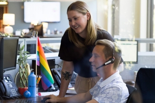 One person on the phone working with another person at a desk