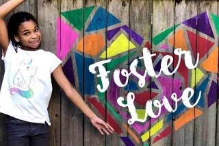 Photo of a girl at a fence painted with Foster Love