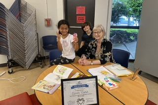 Two kids with an adult volunteer in a classroom