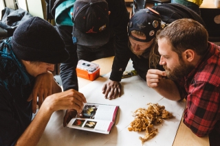 Photo of men gathered looking at a book