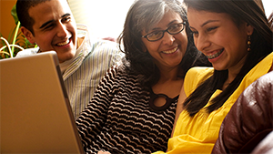 Thumbnail photo of a family smiling while looking at a laptop