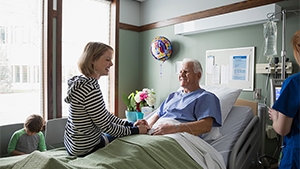 Thumbnail photo of a woman visiting an elderly man in the hospital